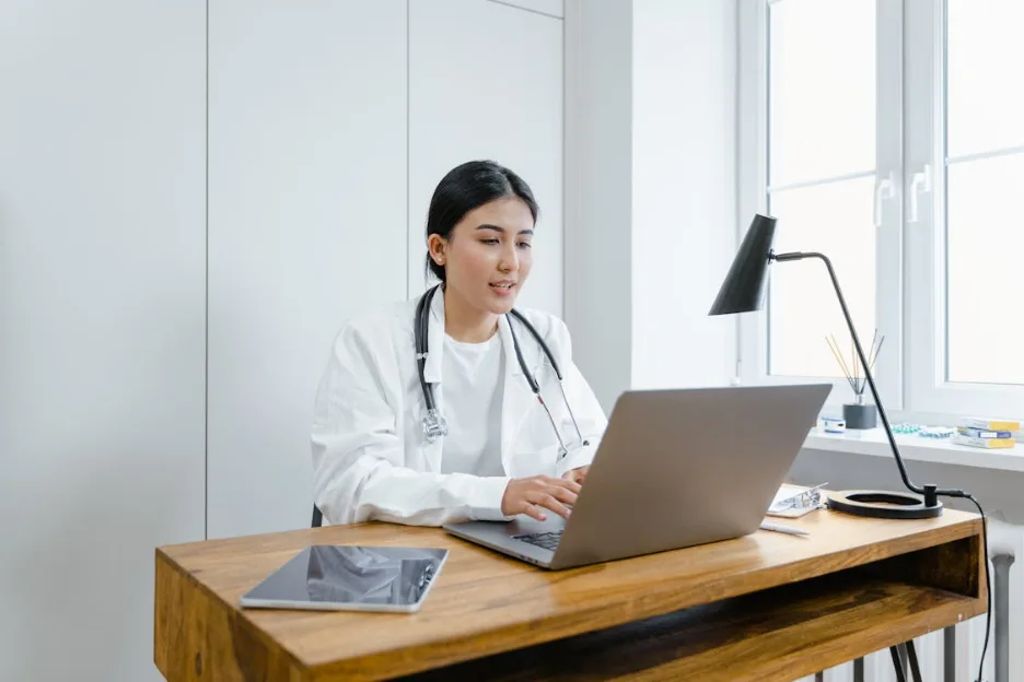 Doctor reviewing patient treatment plans on a laptop in a modern clinic setting