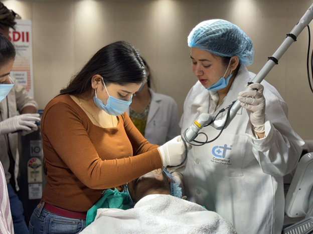 Close-up of a patient receiving hair treatment with tools and a professional in a mask.